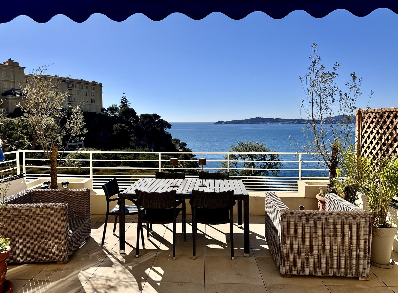 La terrazza dell'appartamento con un tavolo da pranzo e divani affacciati sulla baia verso Cap-d'Ail