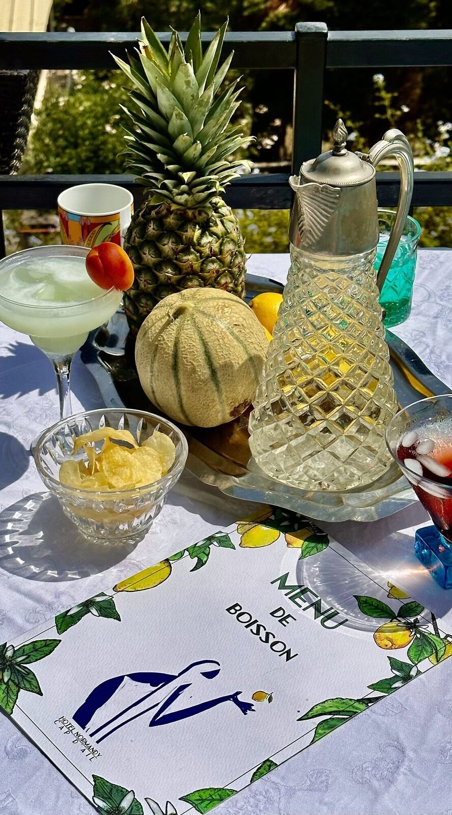 A glass of café crème held up against the sea on the terrace