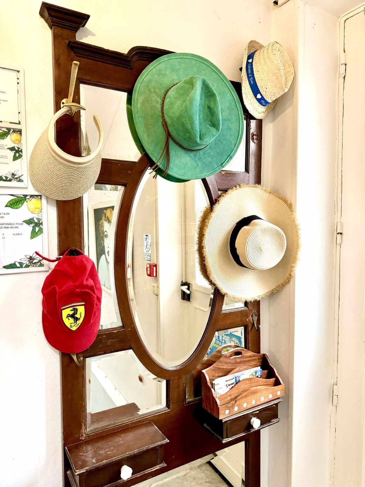 Cappelli di paglia e un cappellino Ferrari appesi all'attaccapanni dell'ingresso